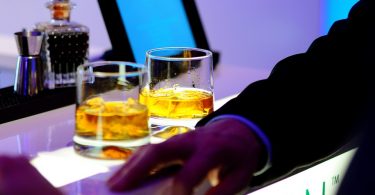 Home a una barra d'un bar amb dos gots de whiskey